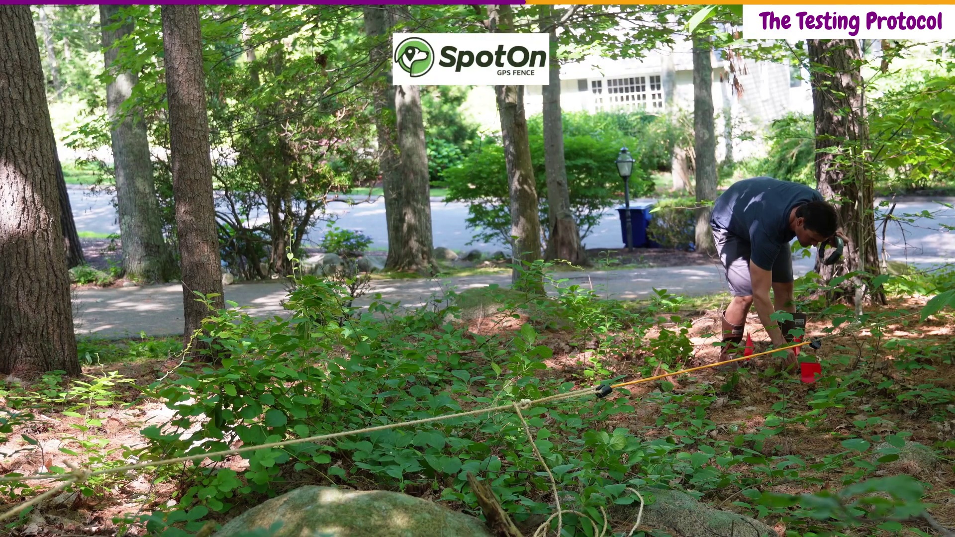 Zach Lovatt setting up the GPS fence boundary testing protocol with rope line and red flags under dense tree cover