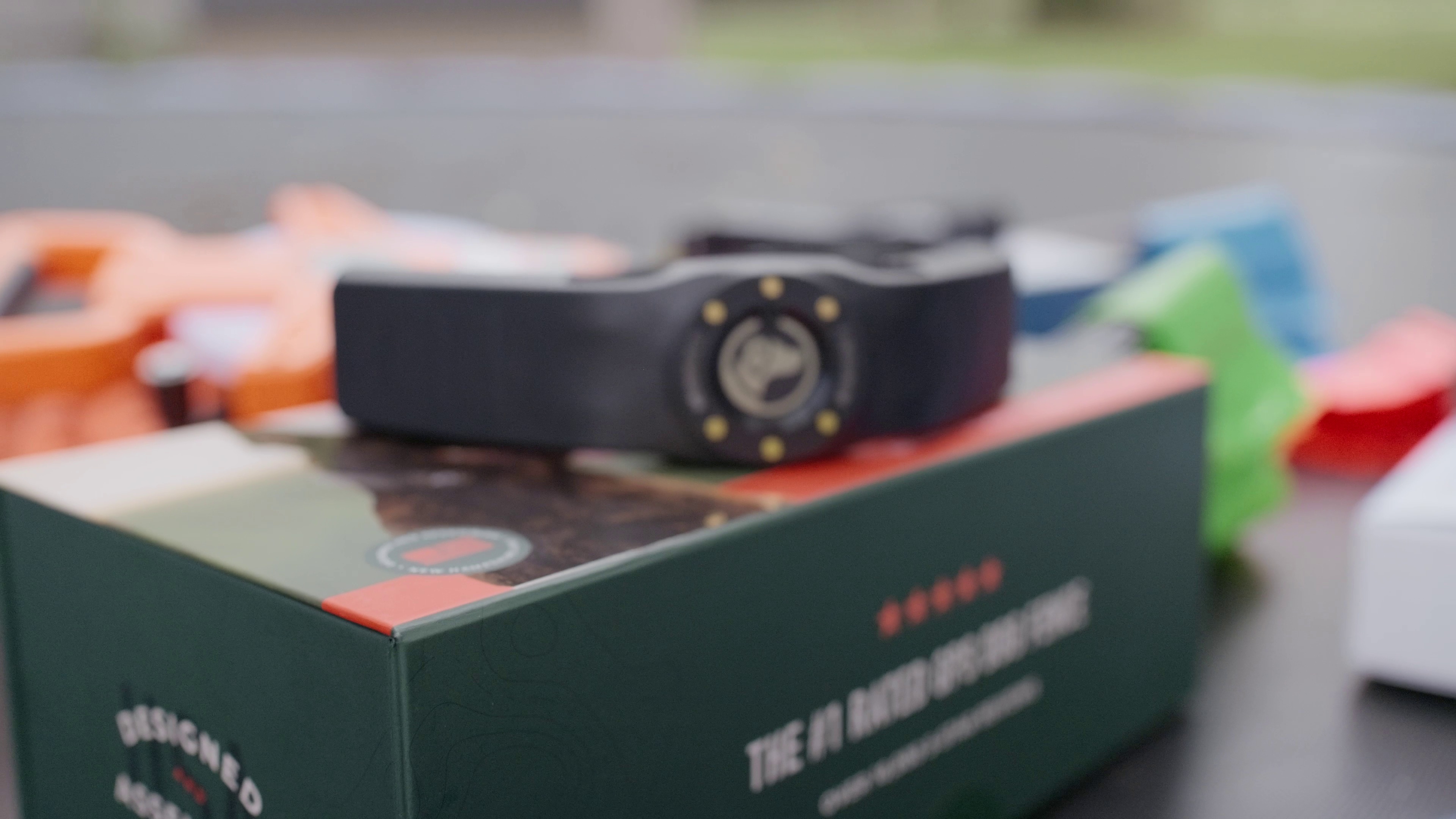 SpotOn Nova collar sitting on its retail box with colored testing flags visible in the background